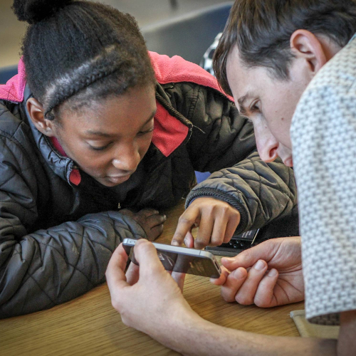 A volunteer helping a member of the public with their phone